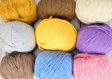 Örgü örmek için çok renkli yün toplar, üç sıra halinde yan yana yatıyorlar..