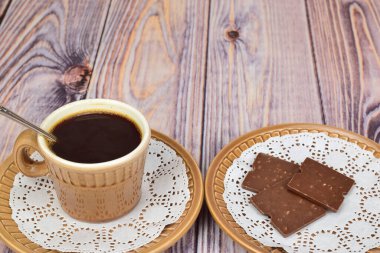 Sade kahve ve çay kaşığı olan bir kupa çay tabağında kalır. Bir sonraki tabakta fındıklı çikolata parçaları var..