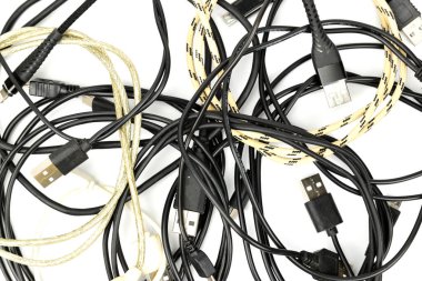 Halkalara bükülmüş ve beyaz bir yüzeye istiflenmiş mobil cihazlar için kablolar yükleniyor