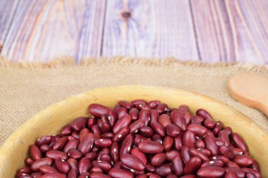 Bir kase çiğ fasulyenin yan görüntüsü. Kase, ahşap bir yüzey üzerindeki kaba bir peçeteye oturur..