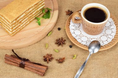 Tahta kesme tahtasının üzerinde bir parça ballı kek, çay tabağında bir fincan sade kahvenin yanında..