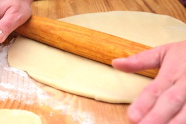 Kadın eli hamuru oklavalı ince bir krepe çeviriyor.