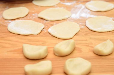 Hamur parçaları küçük kreplere sarılmış. Birkaç yuvarlanmamış parça yan yana yatar..