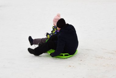 Kızıyla birlikte şişme kar tüpünde kayan bir adam.