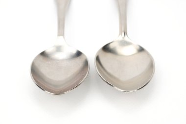 Beyaz bir arka planda baş aşağı duran iki yemek kaşığı ön görünümü