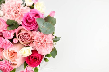 Güller ve karanfiller yemyeşil dekoratif yapraklarla süslü bir bukette birbirine bağlıdır..