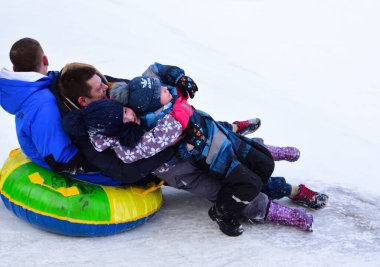 Çocuklu ebeveynler buzlu dağdan gelen şişme bir kızağa biniyorlar.
