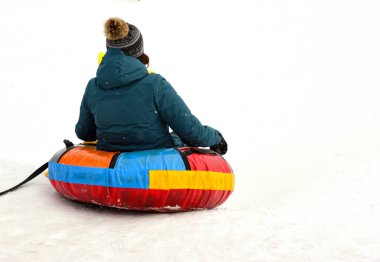 Adam kar kaymasından şişme bir kızağa biniyor.
