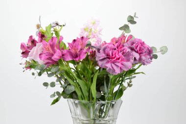 Beyaz arka planda izole edilmiş kristal vazodaki karanfiller ve çanlar.