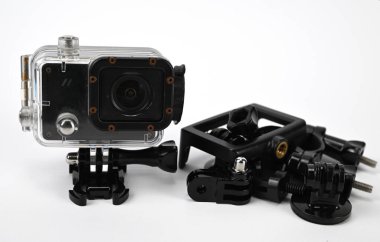 An action camera inside a transparent waterproof box next to a set of accessories.