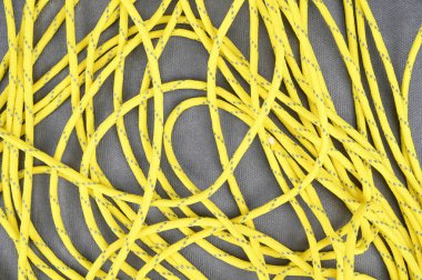 Masa üzerinde dağınık gri çizgileri olan sarı bir paraşüt. Gri arkaplanda sarı kablo.