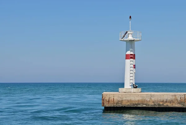 Uzun takviyeli beton iskelenin sonunda bir deniz feneri. Deniz ufku, mavi deniz.