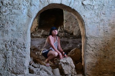 Bir kadın turist harap olmuş antik bir Roma binasının içinde yürüyor ve eski zamanlara hayran. Yarı dairesel kemerli kapı..