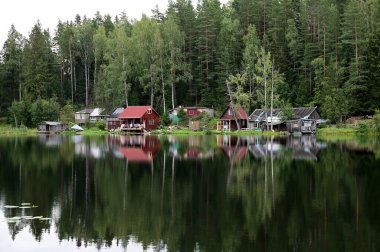 Orman gölünün kıyısında küçük bir köy. Elbiseler çamaşır ipinde kurumuş. Yumuşak suda yansıma.