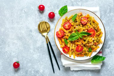 Fusilli - Tavuklu buğday, domatesli kiraz, domates soslu fesleğen, beyaz kâse içinde beyaz beton masa üzerinde Akdeniz mutfağından klasik İtalyan makarnası