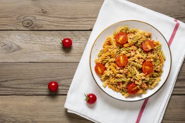 Fusilli - Tavuklu buğday, domates vişneli, fesleğenli domates soslu klasik İtalyan makarnası ahşap masada beyaz kase içinde Akdeniz mutfağı
