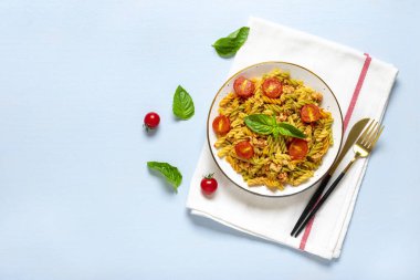 Fusilli - Tavuklu buğday, domates, kiraz, domates soslu fesleğen, beyaz kâse, peçete, çatal mavi ahşap masa üzerinde Akdeniz mutfağından klasik İtalyan makarnası