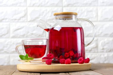 Böğürtlenli bitki çayı, ahududu, nane yaprağı ve cam çaydanlıkta ambar çiçeği ve ahşap masa üzerinde fincan soğuk vitamin içeceği Rustik tarzı..