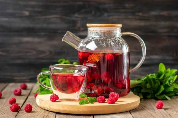 Böğürtlenli bitki çayı, ahududu, nane yaprağı ve cam çaydanlıkta ambar çiçeği ve ahşap masa üzerinde fincan soğuk vitamin içeceği Rustik tarzı..