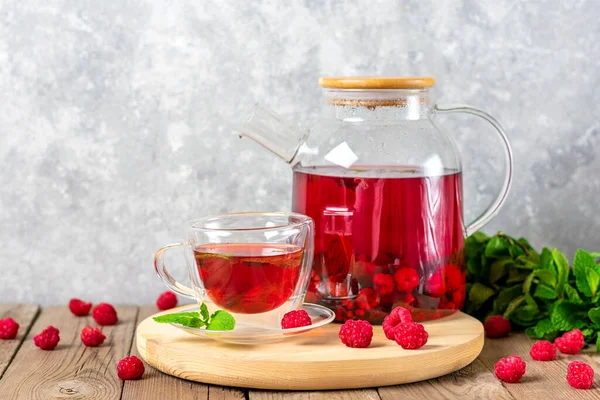 Böğürtlenli bitki çayı, ahududu, nane yaprağı ve cam çaydanlıkta ambar çiçeği ve ahşap masa üzerinde fincan soğuk vitamin içeceği Rustik tarzı..