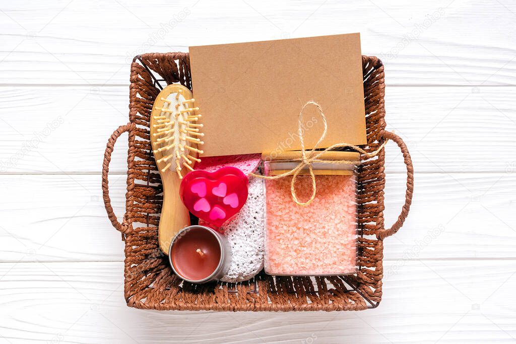 Care box Set of eco-friendly cosmetics Bath salt, wooden comb, pumice stone, aroma candles, handmade soap in shape of heart, sponge for washing on white background Gift for girlfriend, mother Top view