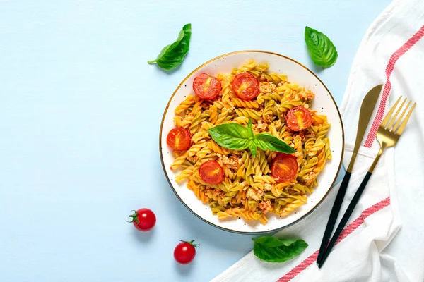 Fusilli - Tavuklu buğday, domates vişneli, fesleğen soslu domates soslu klasik İtalyan makarnası mavi ahşap masada Akdeniz mutfağı