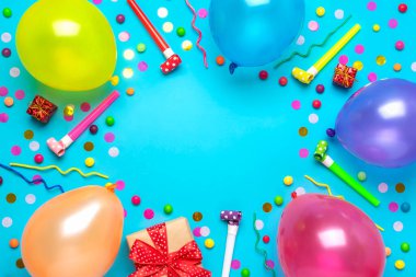 Parti konfetileri, balonlar, flamalar, pokerler ve mavi arka planda süslemelerle dolu kırmızı hediye kutusu olan renkli bir parti çerçevesi. Tatil kartı düz yatıyordu Üst görünüm Mutlu yıllar parti konsepti