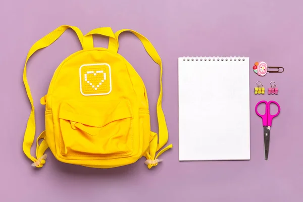 Okula dönmek, eğitim kavramı. Okul gereçleri içeren sarı sırt çantası - dizüstü bilgisayar, kalem, klips, makas mor arkaplan üzerinde izole edilmiş Üst görünüm fotokopi alanı düz kompozisyon Banner — Stok fotoğraf