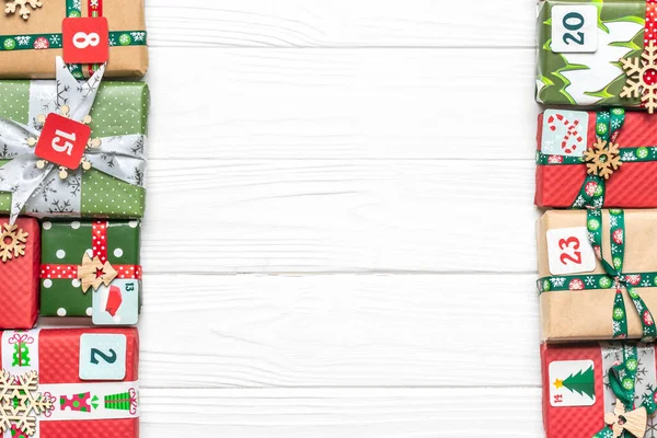 Fatto a mano avvolto rosso, scatole regalo verdi decorate con nastri, fiocchi di neve e numeri, decorazioni natalizie e decorazioni su tavola bianca Concetto di calendario dell'avvento di Natale Vista dall'alto Flat lay Holiday card — Foto Stock