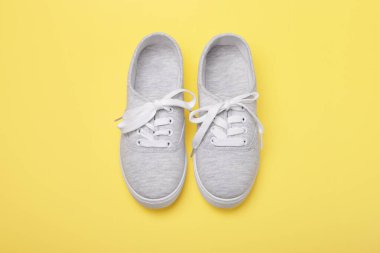 Sarı arka planda bağcıklı gri spor ayakkabılar. Düz görünüm