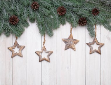 Ağaç dalları, çam kozalakları ve yıldızlı Noel ağacı arka planı.