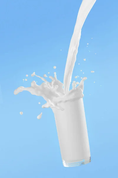 Giet melk in glazen beker met spetteren op blauwe achtergrond — Stockfoto