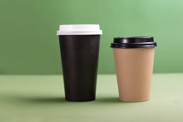 Två papper koppar kaffe eller te på grön bakgrund — Stockfoto