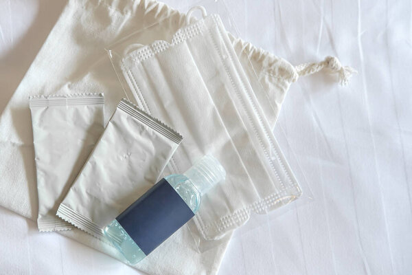 Антикоронавирусный (COVID 19) набор для личной гигиены на белой хлопчатобумажной ткани. Сумка из натуральной хлопчатобумажной ткани, алкогольные салфетки, бутылка алкогольного геля и гигиеническая маска для лица, копировальное место для текста