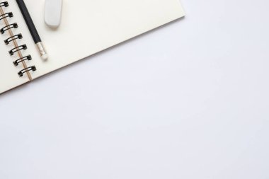 Open blank notebook with pencil and eraser on white background, flat lay, top view of workspace,  copy space for text.