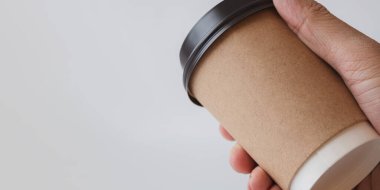 Man Hand 'in Gri Arkaplanda Kahverengi Kağıt Kahve Kupasını Tutuşu, Logo Tasarımı için Mockup Şablonu, Metin için Boşluğu Kopyalama.