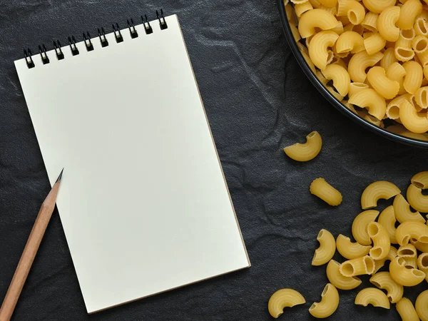 Ouvert Carnet Vide Crayon Avec Pâtes Macaroni Sur Fond Noir — Photo