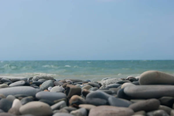 ビーチだ。小石のビーチから海と滑らかな地平線のビュー。手前は大きな小石。. — ストック写真