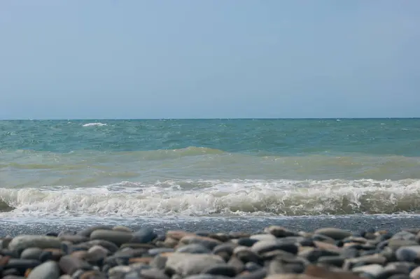 A Fekete-tenger tengeri hulláma kavicsos strand. Sima horizont, kék ég. — Stock Fotó