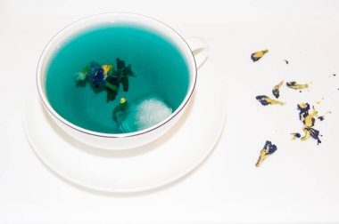 Ruh hali rengi mavi. Beyaz bir fincan çay bardağındaki mavi çay. Beyaz bir fincan tabağı ve beyaz bir tepside duruyor. Yararlı içkiler, iyileştirici özellikler. Beden eğitimi. Çay partisi..