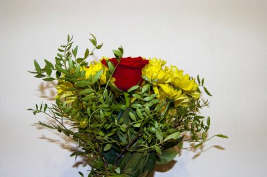 Kırmızı güllerden yapılmış bir buket çiçek ve ambalajsız sarı kasımpatılar.