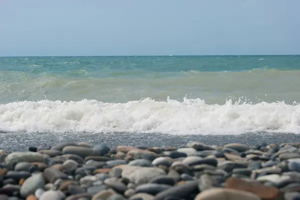 A Fekete-tenger tengeri hulláma kavicsos strand. Sima horizont, kék ég. — Stock Fotó