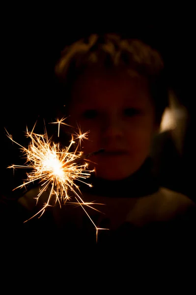 Burning bengal fire on a dark background in a child in his hand, make a wish for the new year, Christmas miracles and divination, baptism. Traditions