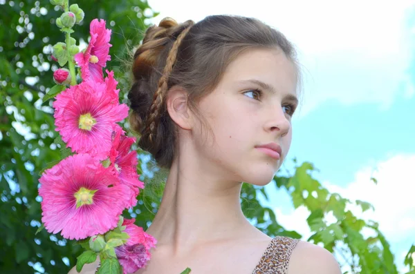 Fille avec coiffure et hollyhocks rose — Photo