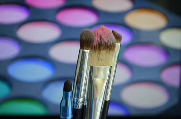 Pinceles para maquillaje sobre una paleta de fondo con sombra de ojos — Foto de Stock