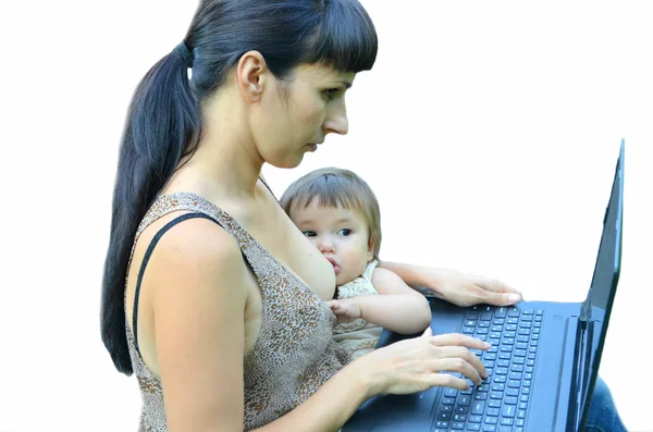 A woman holds a baby in her arms with a laptop — Stock Photo, Image