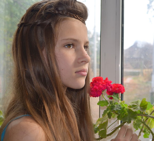 Girl near the window with geraniums