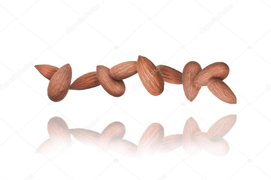 Whole Almonds nuts in a row isolated on a white Background floats in the air. Food Levitation Concept. Mirror reflection with Copy Space for Text.