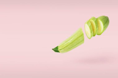 Tek bir sebze iliği taze taze dilimlenmiş. Pembe arka planda uçan küçük parçalar. Havaya yükselme yiyeceği kavramı. Metin için alanı kopyala.