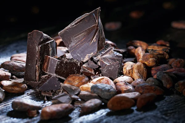 Chocoladestukjes met stukjes cacaobonen op een houten tafel — Stockfoto